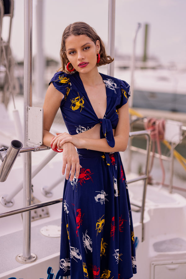 Take New Orleans home with you the sweet Petal Tie Top featuring a petal sleeve and an adjustable tie front! Layer over one of the sleeveless dress or romper styles to give them a different look, or pair with matching bottoms in our 1930s 1940s Crawfish novelty print of red, yellow, and white crustaceans on a deep navy blue background as a nod to Schiaparelli's lobster.