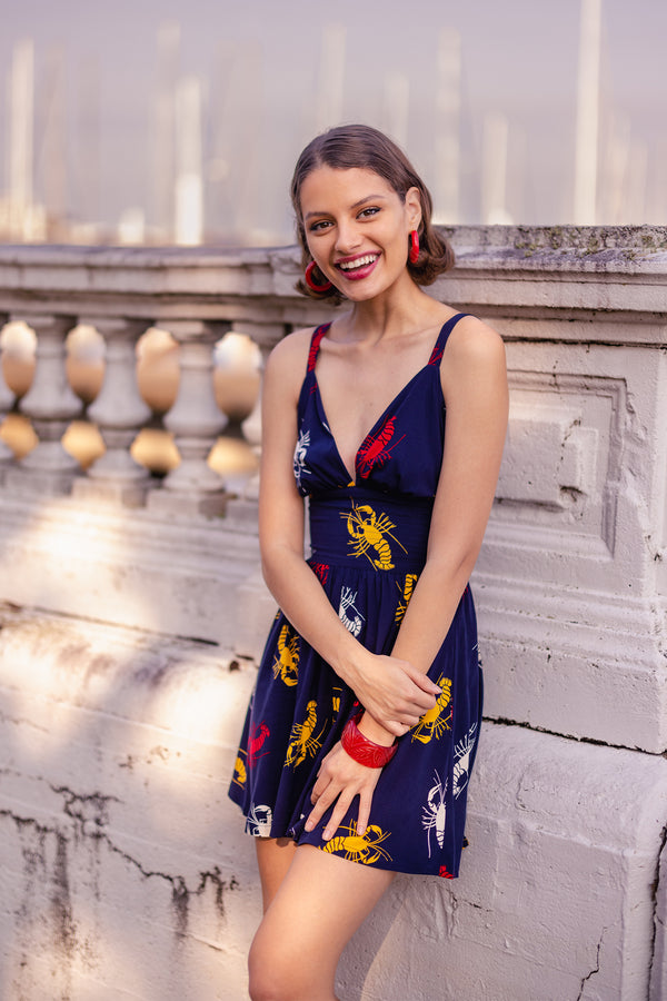 The 'Crawfish' Minda Romper is a mash-up of our popular high waisted shorts paired with the 'Minda' style top with adjustable button straps and removable halter tie. Featuring a fun 1930s/40s novelty print of red, yellow, and white crustaceans on a deep navy blue background as a nod to Schiaparelli's lobster, the vintage-inspired Minda Romper boasts a deep v neck, fitted undercuts, and side pockets.
