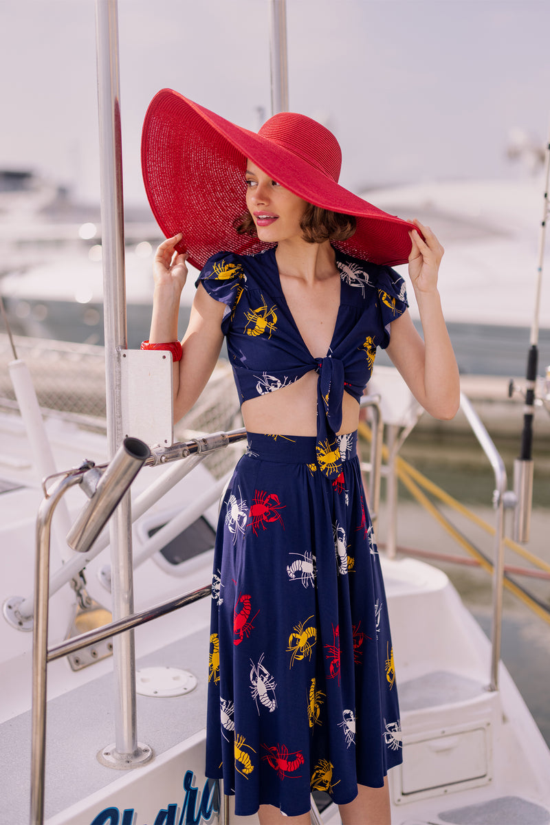 Take New Orleans home with you the sweet Petal Tie Top featuring a petal sleeve and an adjustable tie front! Layer over one of the sleeveless dress or romper styles to give them a different look, or pair with matching bottoms in our 1930s 1940s Crawfish novelty print of red, yellow, and white crustaceans on a deep navy blue background as a nod to Schiaparelli's lobster.